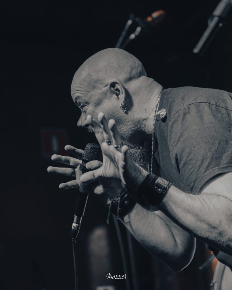 Robert Lowe leaning into the microphone, black and white