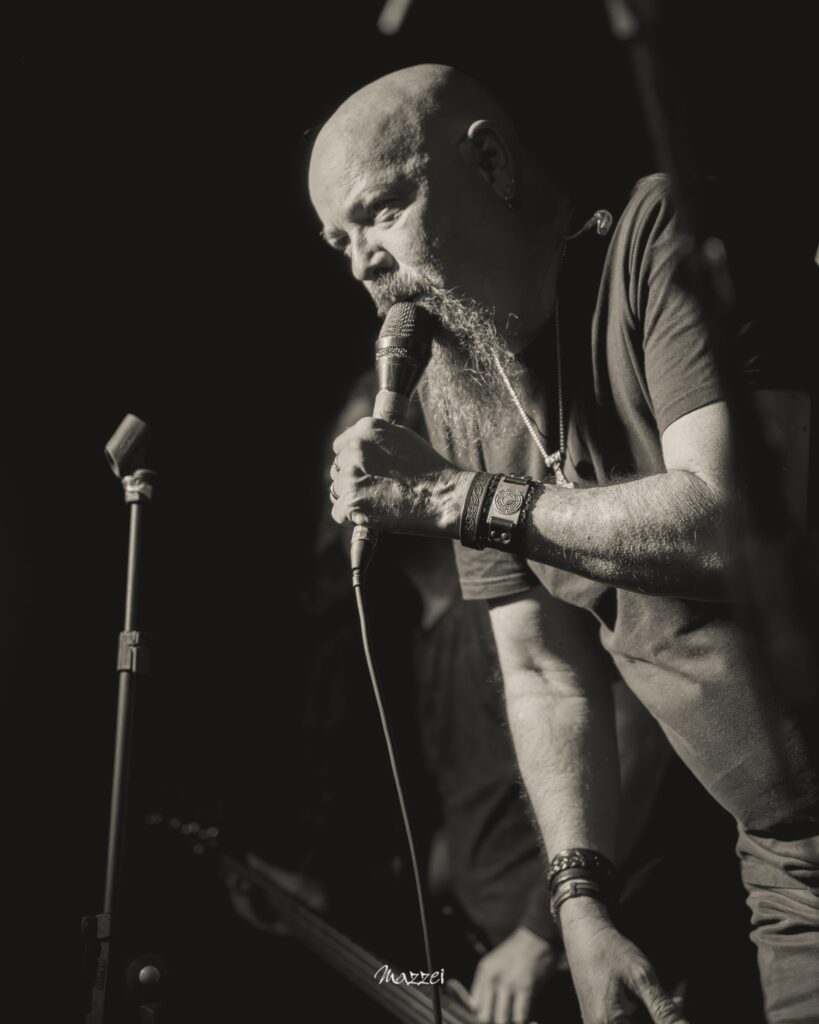 Robert Lowe singing into the microphone, black and white