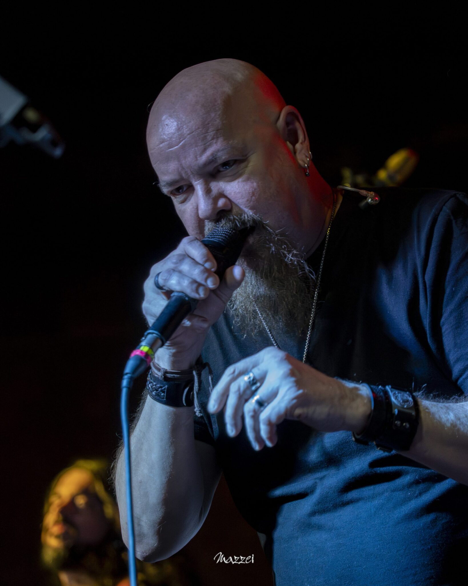 Robert Lowe singing, close-up under blue light