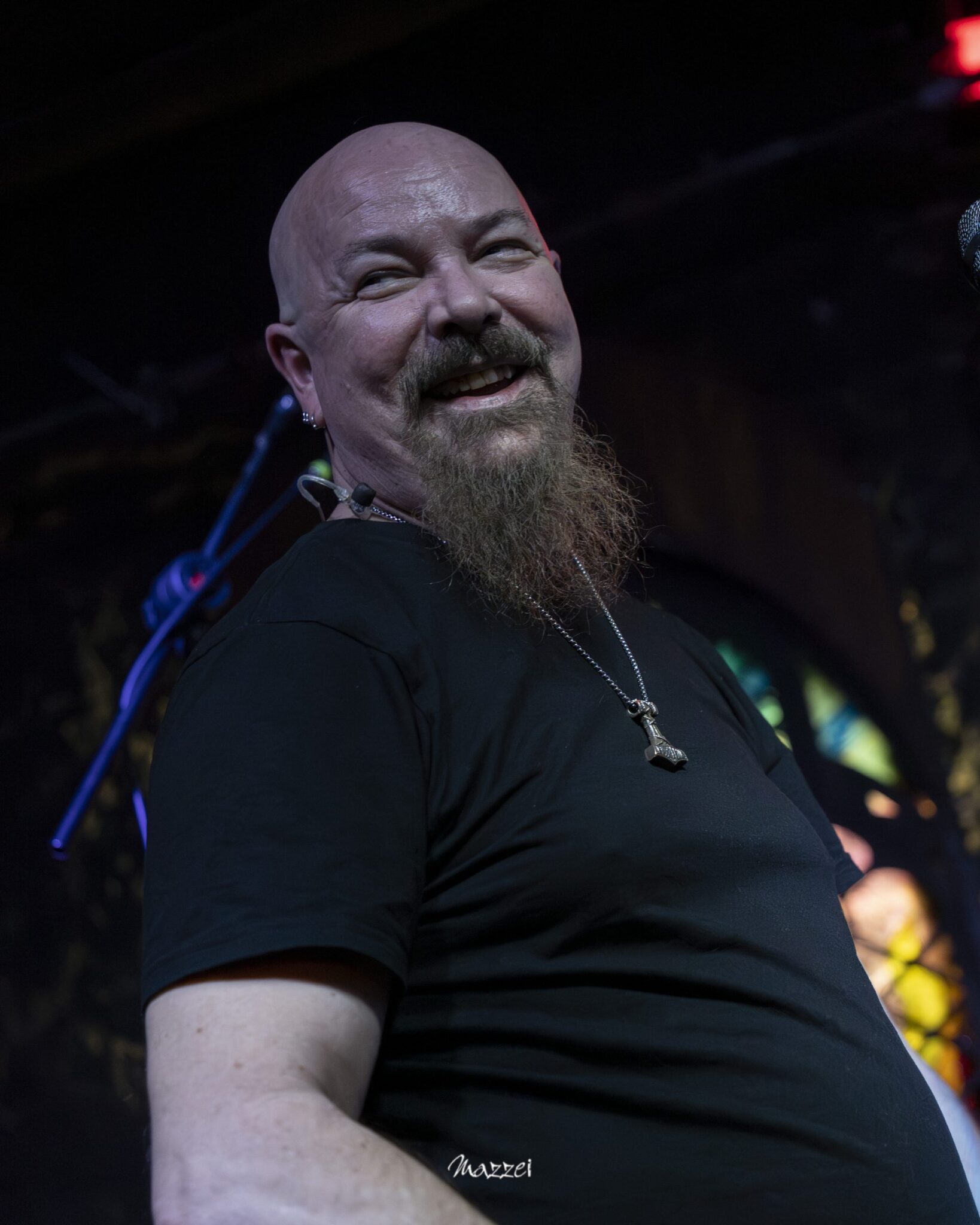Robert Lowe smiling on stage in front of stained glass windows