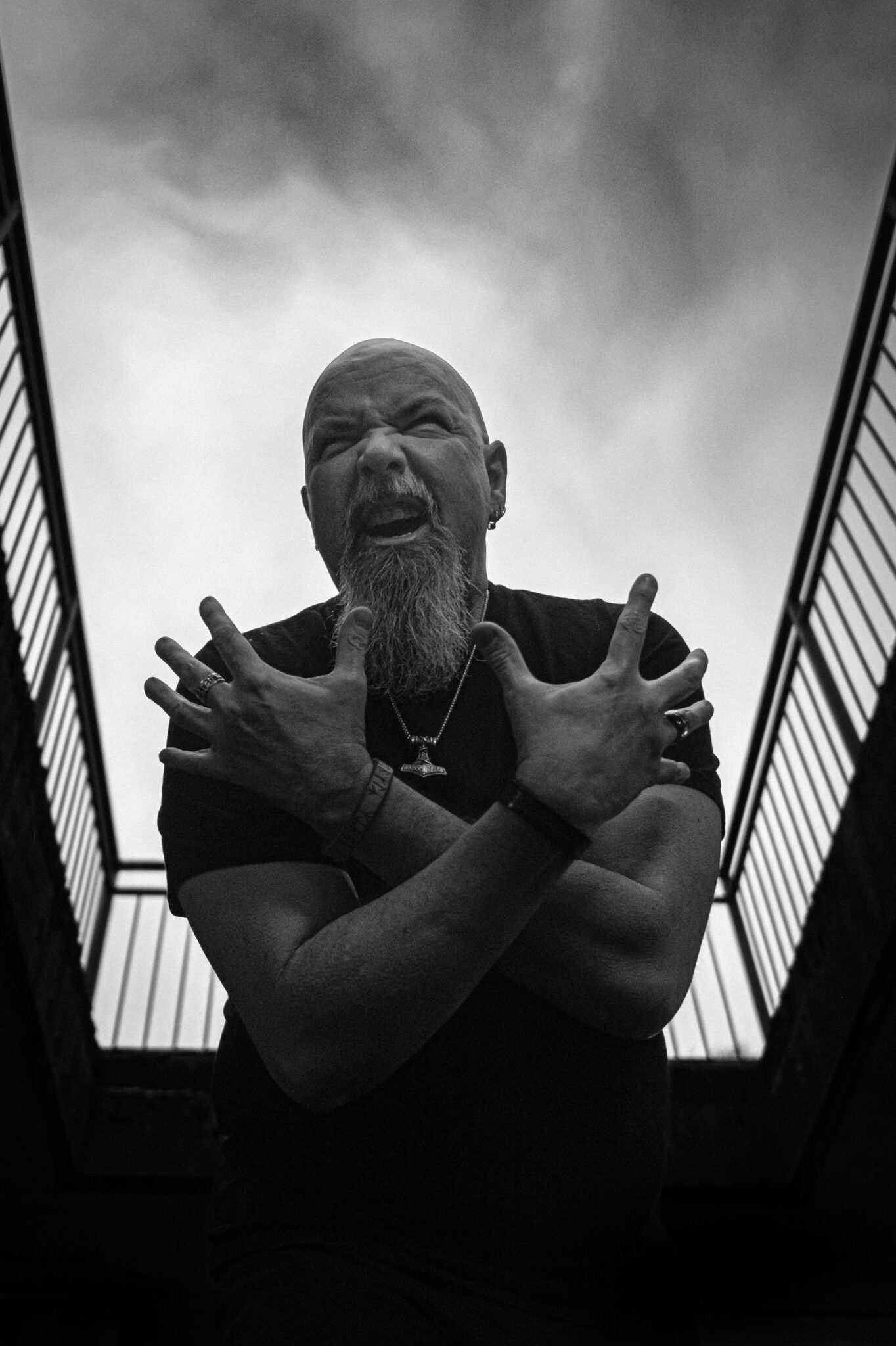 Robert Lowe shouting at the top of an outdoor stairway, seen from below